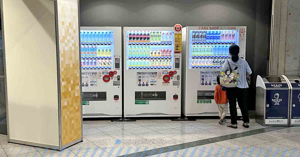 東京ゲームショウ2024、ファミリーゲームパーク入口付近に設置された自動販売機。混雑もなく、親子がゆっくり飲み物を選んでいる様子。