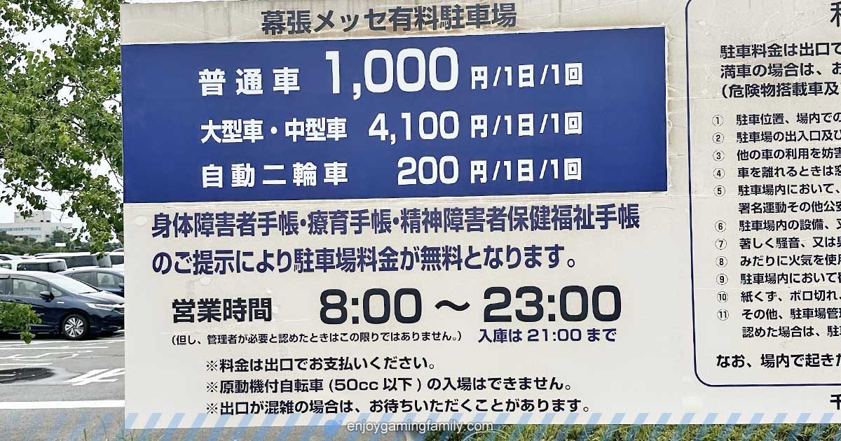 幕張メッセ有料駐車場の料金案内看板。普通車は1日1回1,000円、大型車・中型車は4,100円、自動二輪車は200円。身体障害者手帳などの提示で駐車料金が無料になる旨も記載。営業時間は8:00〜23:00（入庫は21:00まで）。